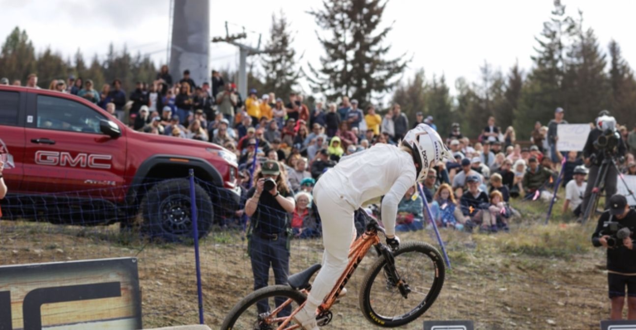 Downhill rider passes a branded truck display